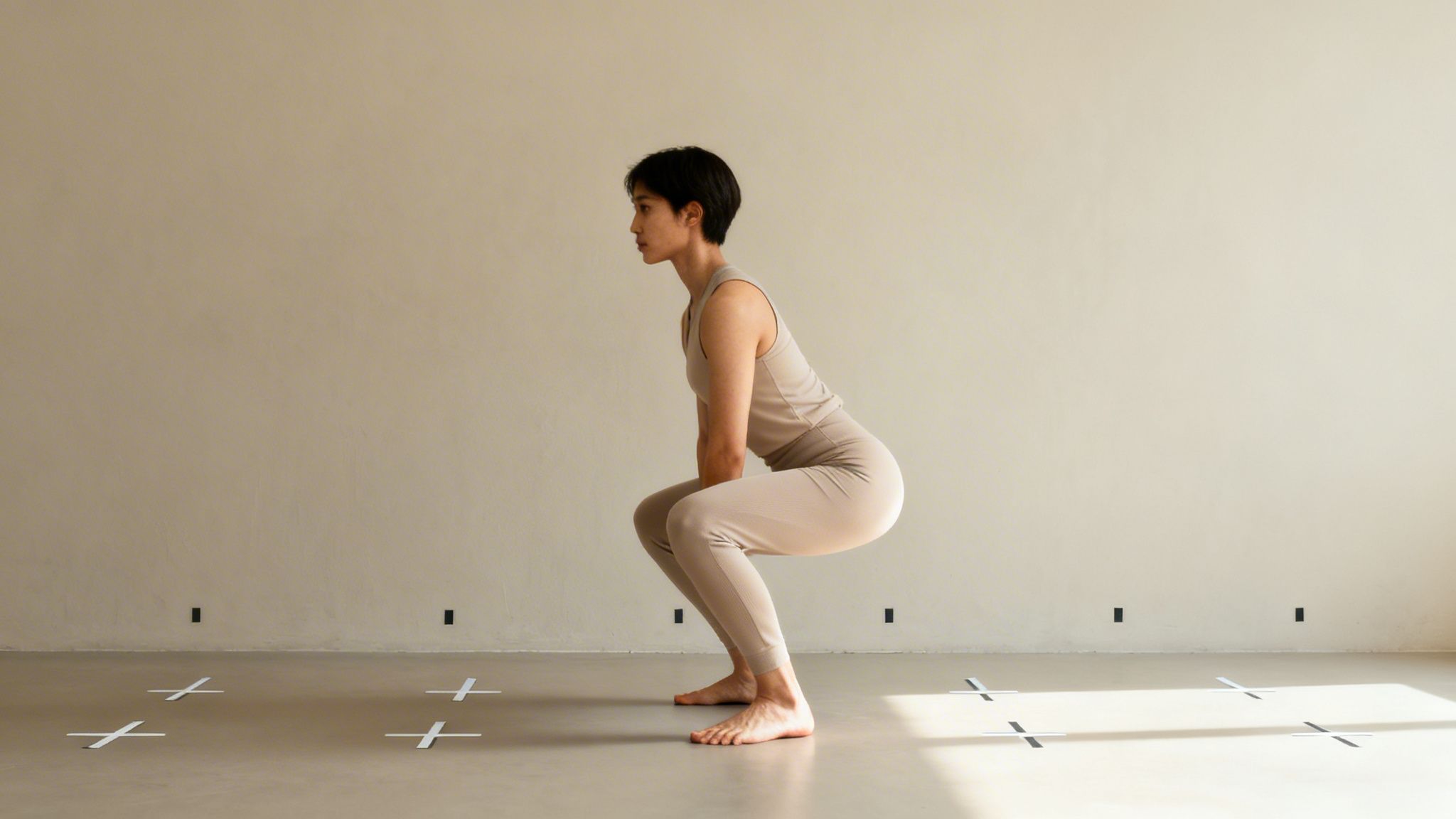 A woman performs a squat exercise in a studio, demonstrating good form for mobility.